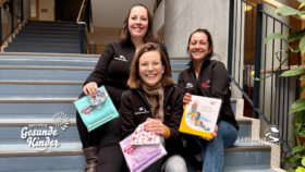 drei sympathis lachende junge Frauen sitzen auf einer Treppe